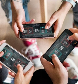 Mãos de três pessoas jogando em seus celulares.